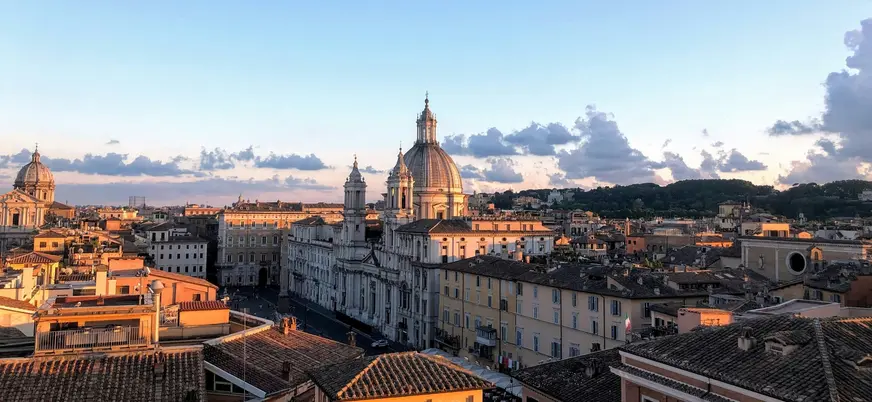 Panorámica de Roma al atardecer con cúpulas históricas y tejados iluminados