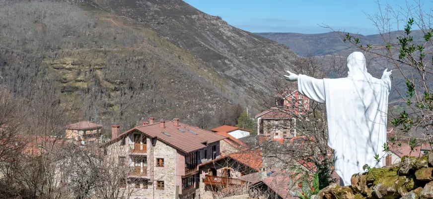 Estatua de Cristo en San Sebastián de Garabandal, con vistas al pueblo y a las montañas de los Valles Pasiegos en Cantabria.