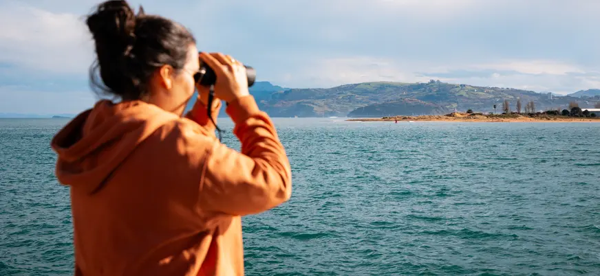 Persona con prismáticos mirando la costa en Santander, Cantabria.