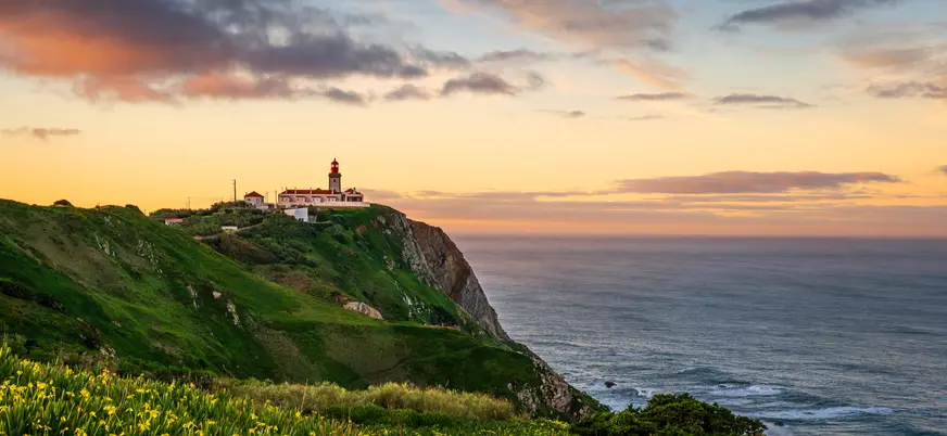 Atardecer en el Cabo da Roca con faro sobre acantilados, Portugal
