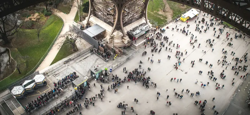 Explanada bajo la Torre Eiffel con visitantes en París, Francia
