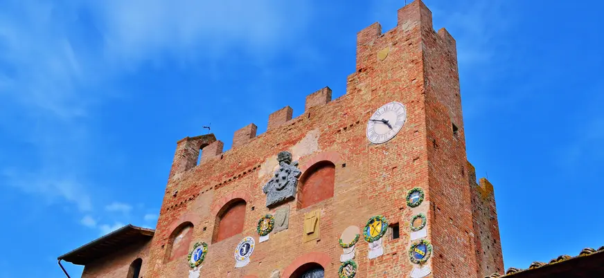 Torre medieval con escudos heráldicos en un pueblo de la Toscana, Italia