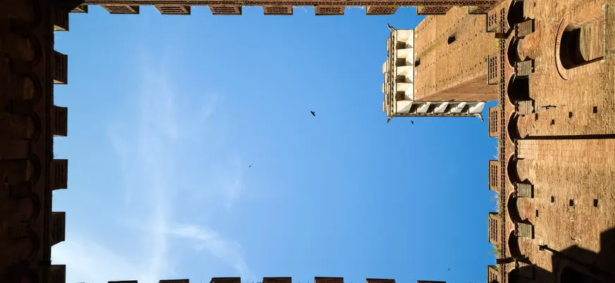 Vista desde patio medieval con torre y cielo azul en la Toscana, Italia