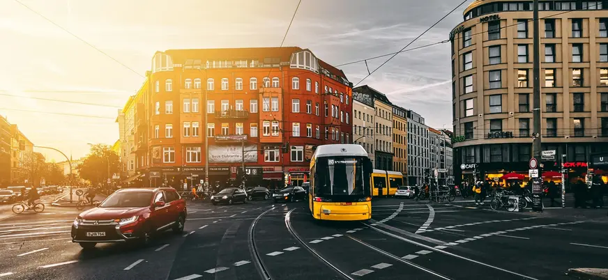 Tranvía amarillo circulando por intersección urbana de Berlín al atardecer.