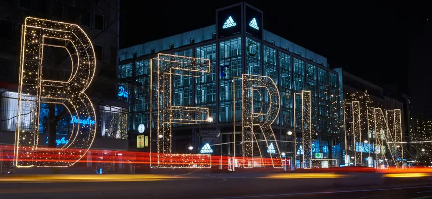 Letrero luminoso gigante de BERLÍN en una calle nocturna con estelas de coches.