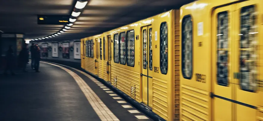 Tren amarillo del U-Bahn de Berlín llegando a una estación subterránea curva.