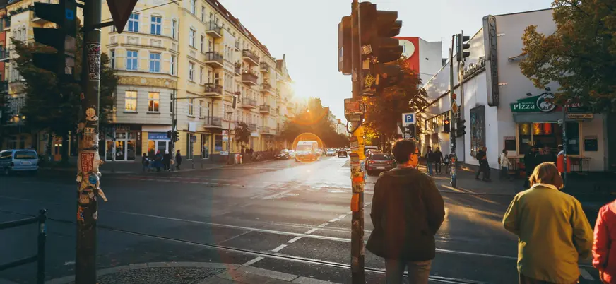 Cruce urbano en Berlín con luz de atardecer, semáforos y arquitectura clásica.