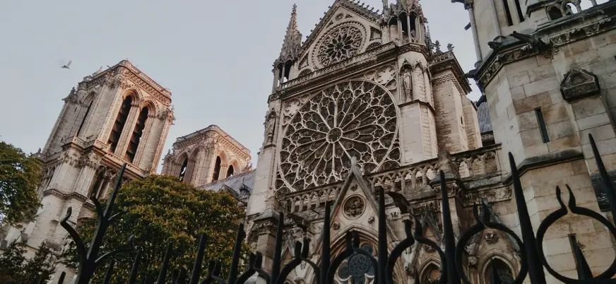 Fachada gótica de la Catedral de Notre Dame en París con rosetón central y torres icónicas vistas desde el exterior.
