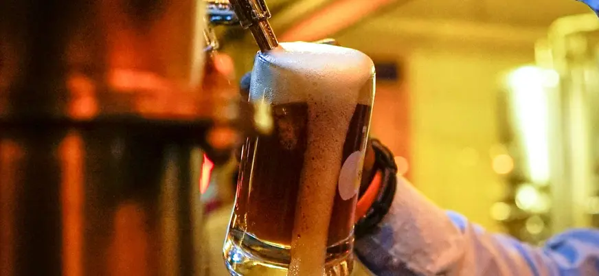 Cerveza artesanal con espuma desbordando el vaso tirada de un grifo en Berlín.