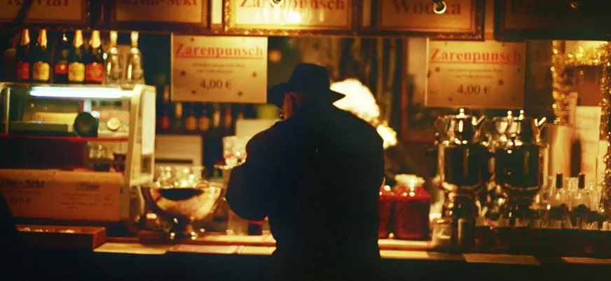 Silueta de hombre con sombrero frente a un puesto de bebidas en Berlín.