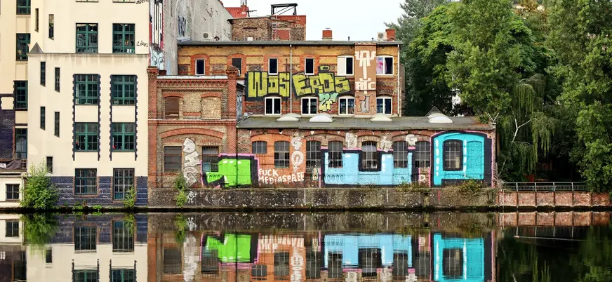 Edificios industriales con grafiti reflejados en el río Spree en Berlín.