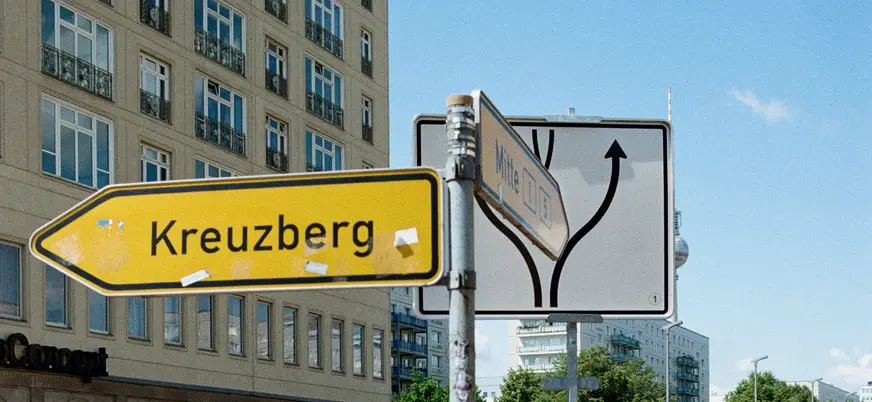 Cartel vial amarillo hacia Kreuzberg frente a edificios y cielo azul en Berlín.