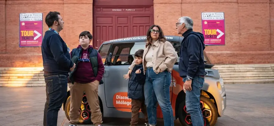 Familia junto a un coche eléctrico frente a la Plaza de Toros de Málaga.