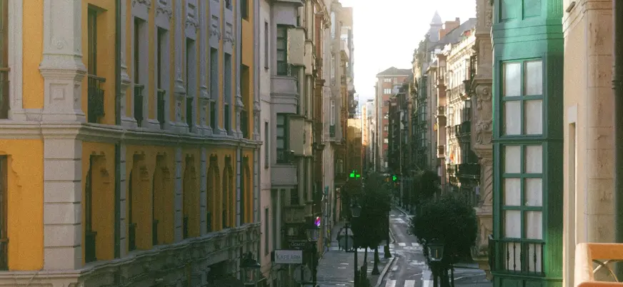 Calle comercial del centro de Gijón con arquitectura clásica y galerías verdes.