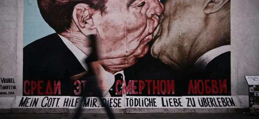 Mural del Beso Fraterno en el Muro de Berlín con persona caminando delante.