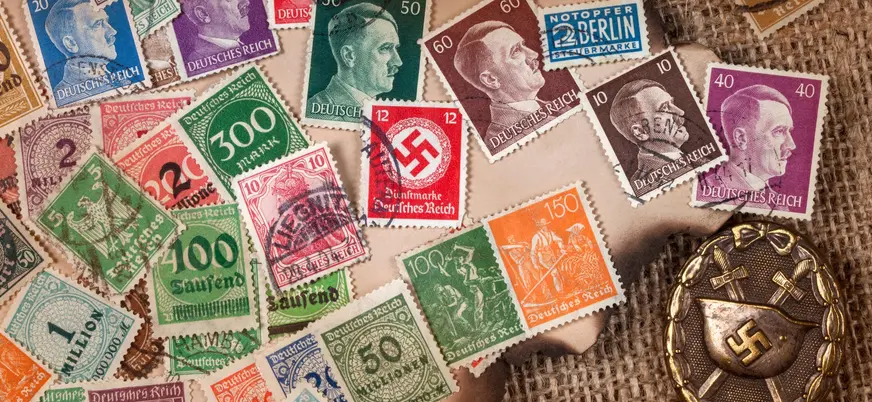 Colección de sellos postales del Tercer Reich y medalla con esvástica nazi.
