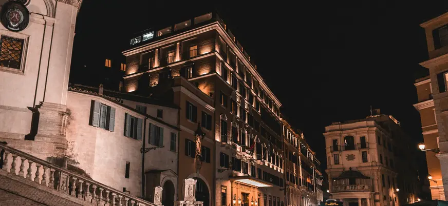 Edificios clásicos y escalinatas iluminadas en una calle de Roma por la noche.