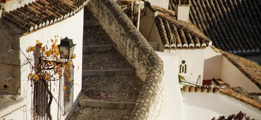 Callejuela empedrada con escaleras y casas blancas típicas del Albaicín, Granada
