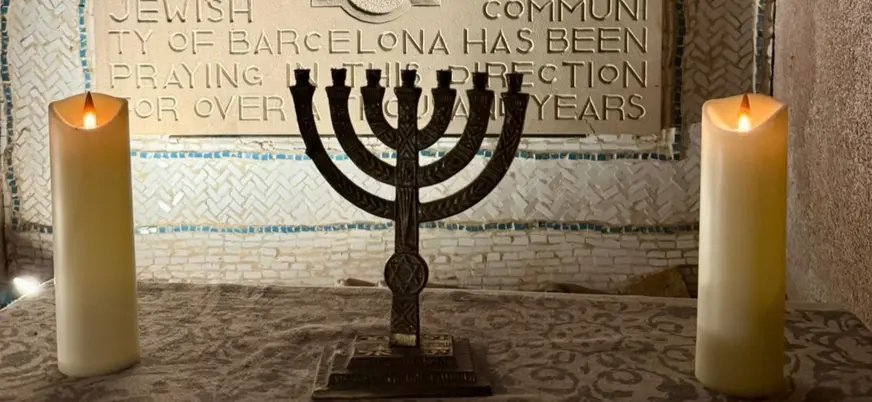 Menorá y velas encendidas ante la placa del Call de Barcelona