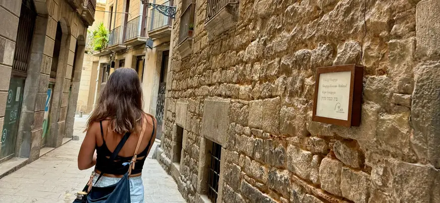 Mujer caminando frente a la Sinagoga Mayor en el Call de Barcelona