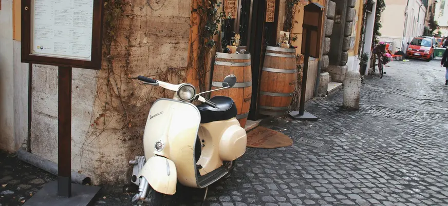 Vespa clásica aparcada en una calle empedrada de Roma