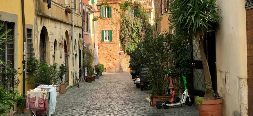 Calle empedrada de Trastevere en Roma con plantas y fachadas antiguas