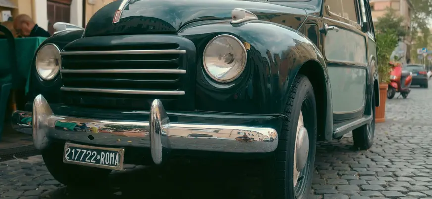 Coche clásico en una calle empedrada de Roma con matrícula histórica italiana