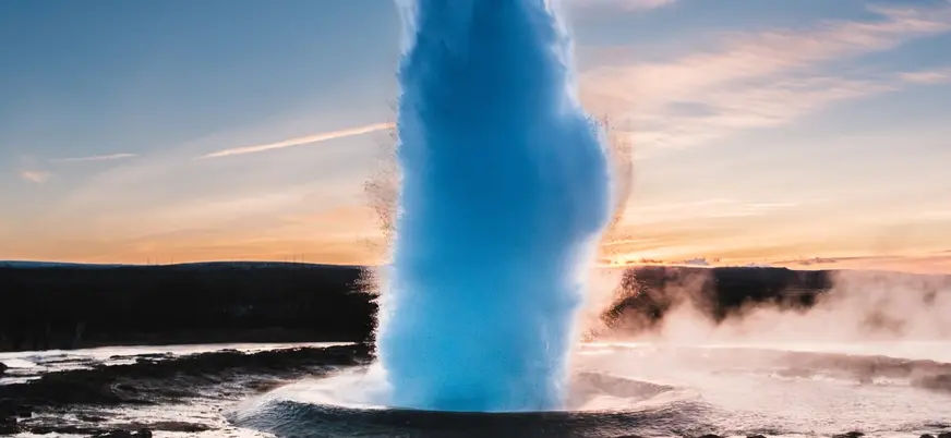 Erupción del géiser Strokkur en el valle de Haukadalur, Islandia, al atardecer entre vapor y aguas termales.