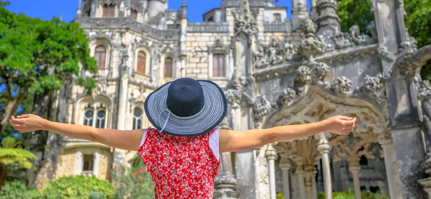 Turista con sombrero frente a la fachada decorada de la Quinta da Regaleira.