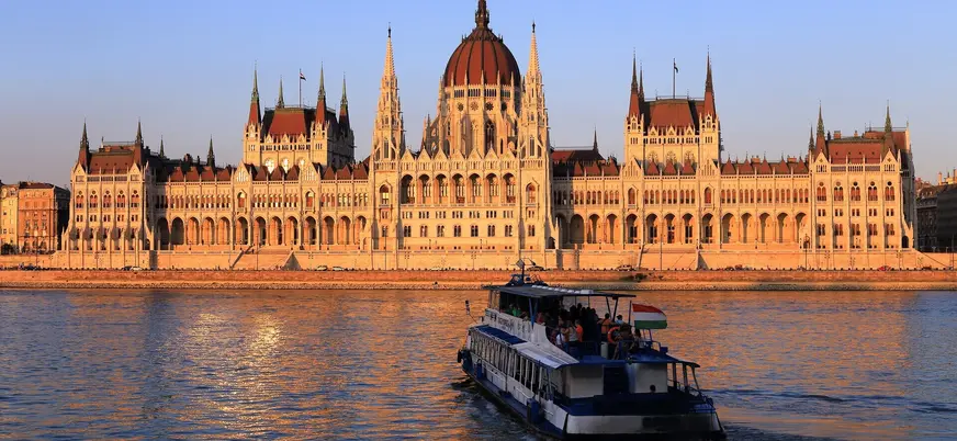 Crucero navegando por el Danubio con el Parlamento de Budapest al atardecer.