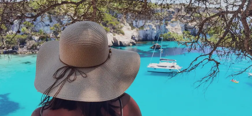 Mujer contemplando catamarán en Cala en Turqueta, Menorca