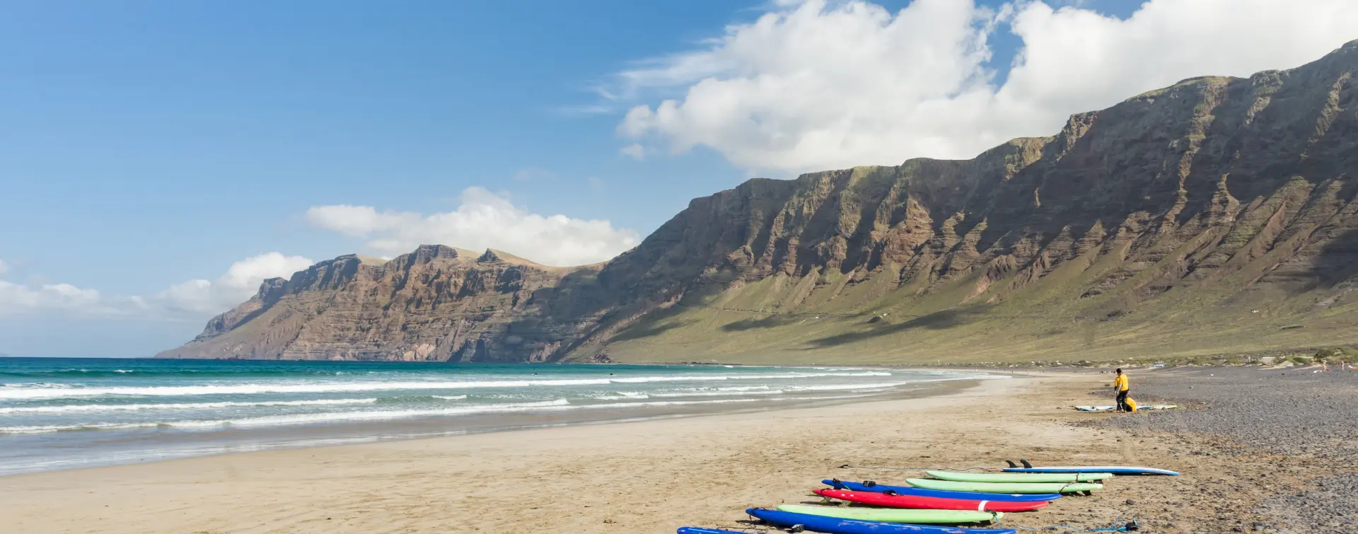 Clase grupal de surf en la playa de Famara