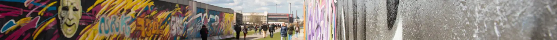Una parte del Muro de Berlín cubierta de grafitis, con turistas paseando a su alrededor