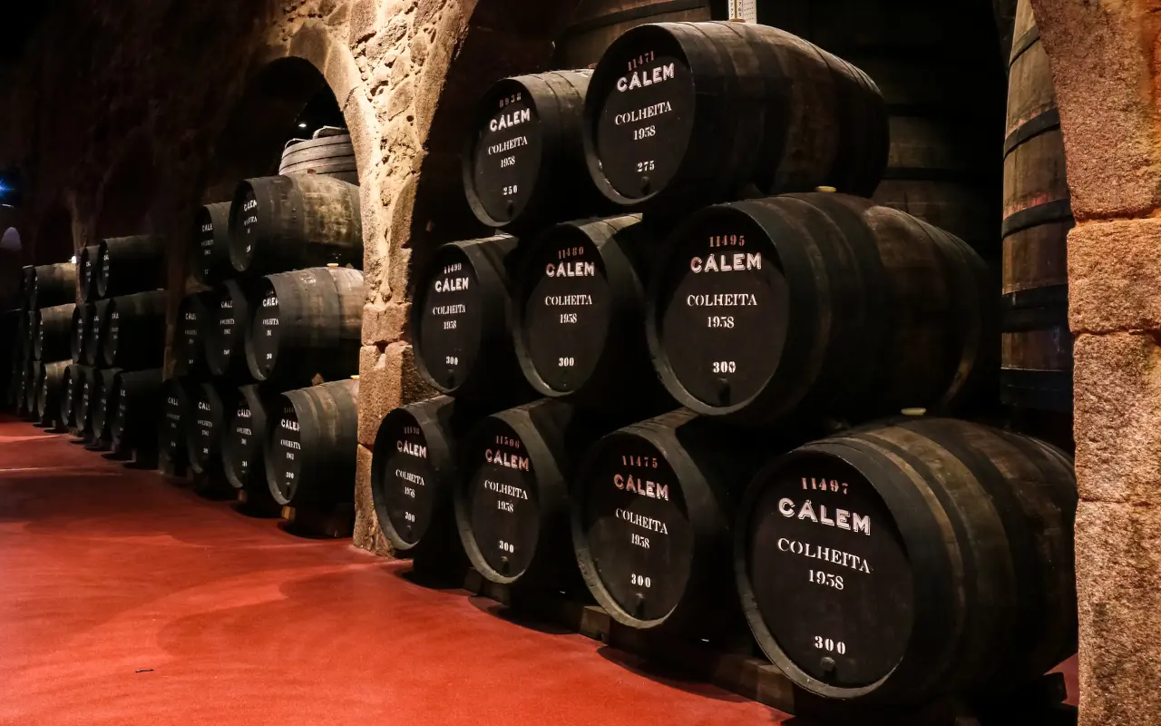 Barricas de vino de Oporto Cálem alineadas en una bodega tradicional de piedra.