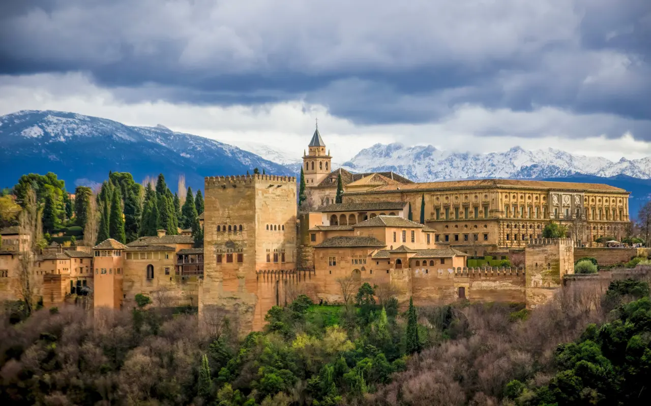 La Alhambra domina la ciudad de Granada, con sus imponentes murallas y torres, rodeada de jardines que reflejan su esplendor.
