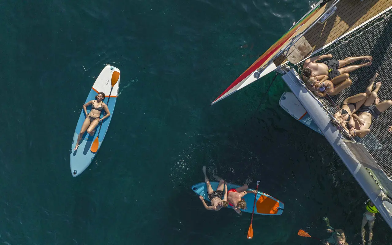 Gente disfrutando del sol mientras se relajan sobre tablas de kayak, flotando en las aguas de la isla de Mallorca.