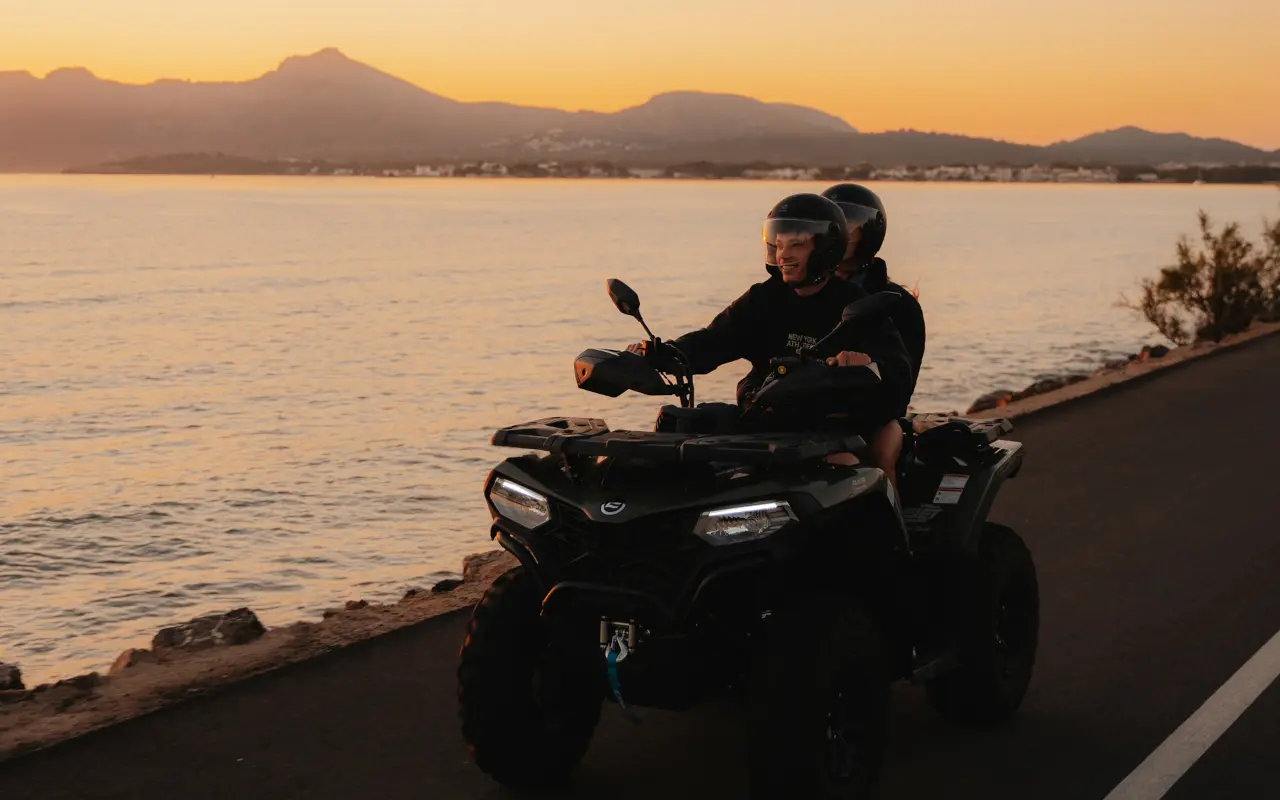 Dos personas montan en quad por la costa mallorquina al atardecer