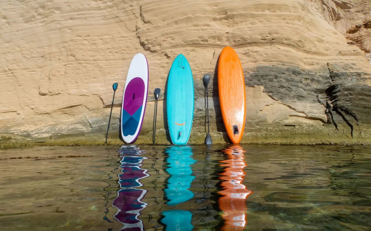 3 coloridas tablas de paddle surf apoyada en una roca de Mallorca