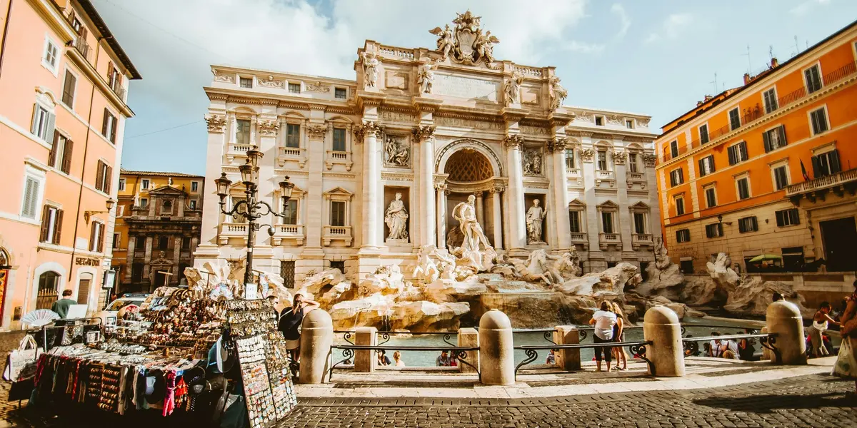Fontana di Trevi en Roma con turistas y puestos callejeros en la plaza