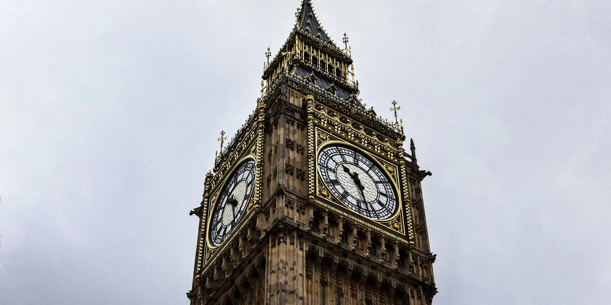 Primer plano de la Elizabeth Tower (Big Ben) en Londres, Inglaterra, con su reloj y detalles dorados bajo cielo nublado.