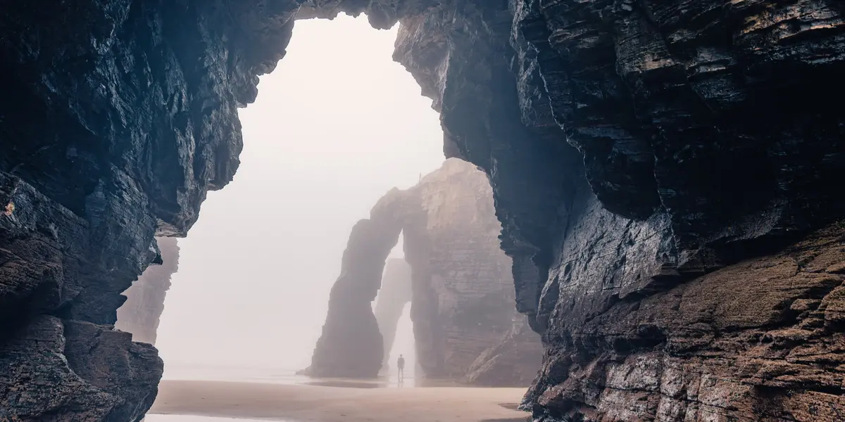 Arcos de piedra y acantilados de la Playa de las Catedrales, Ribadeo, Galicia, con ambiente brumoso.