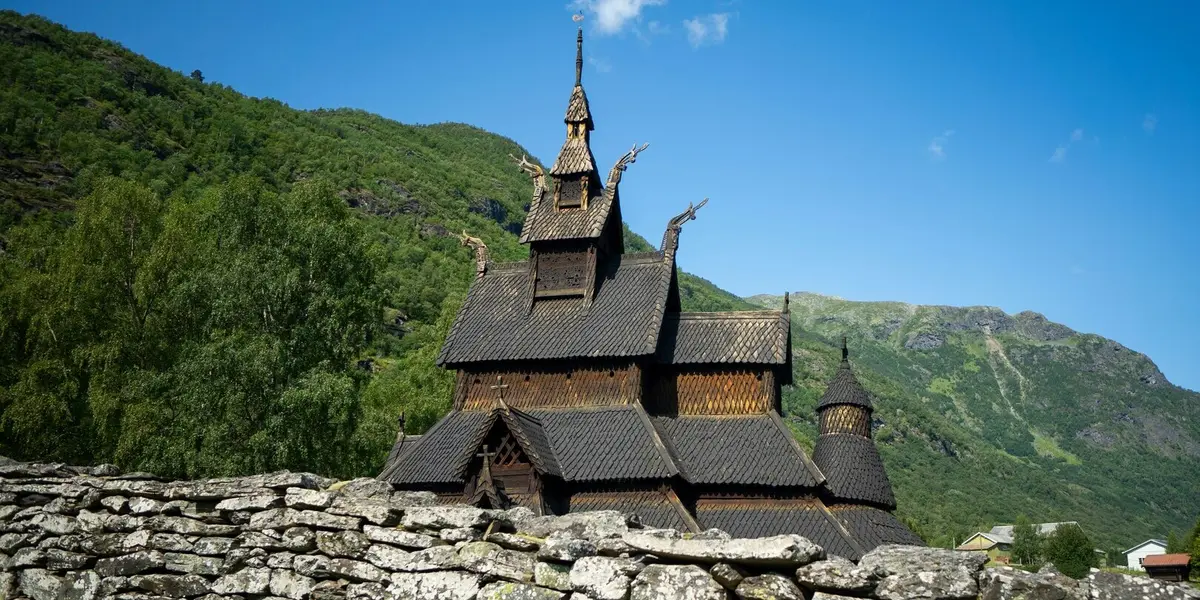 Iglesia de madera de Borgund en Noruega, arquitectura vikinga tradicional rodeada de montañas y naturaleza verde. 
