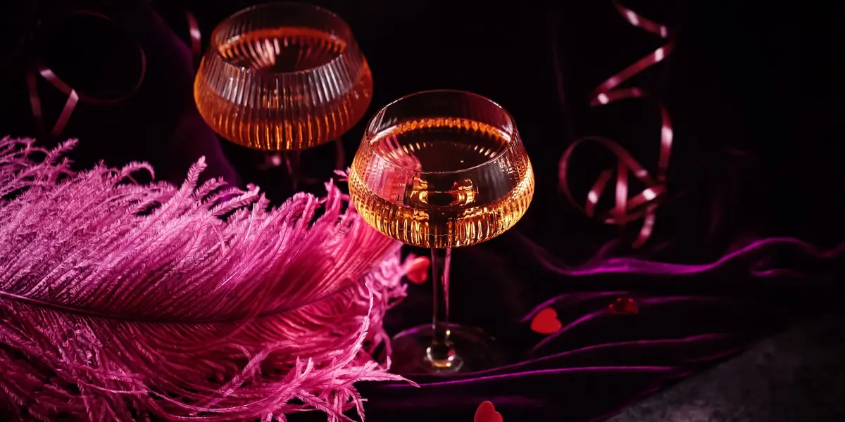 Dos copas de champán sobre terciopelo púrpura con plumas rosas en París