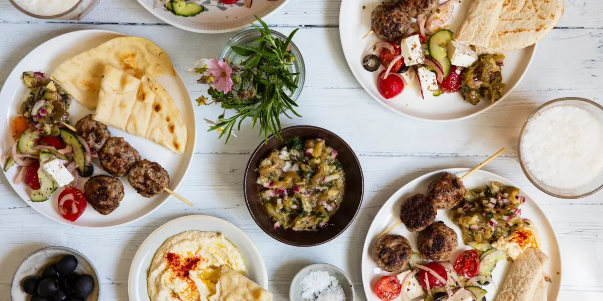 Varios platos de comida griega con brochetas, pan pita y hummus en Atenas