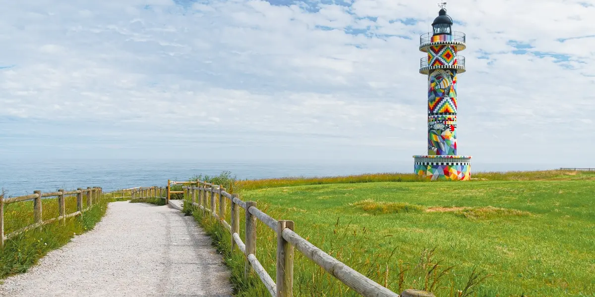 Faro de Ajo con mural colorido junto a un sendero frente al mar en Cantabria