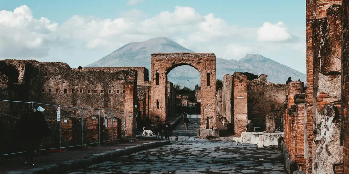 Calle empedrada con arco en las ruinas de Pompeya y el Vesubio al fondo