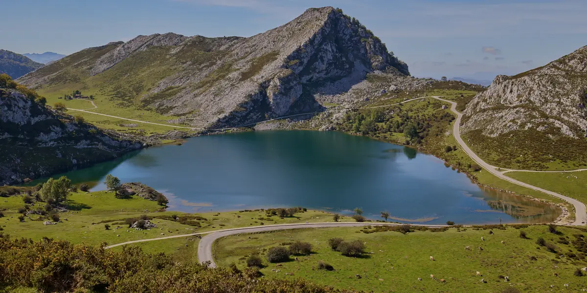Vista aérea del Lago Enol, Lagos de Covadonga en Picos de Europa, Asturias, con montañas y carretera.