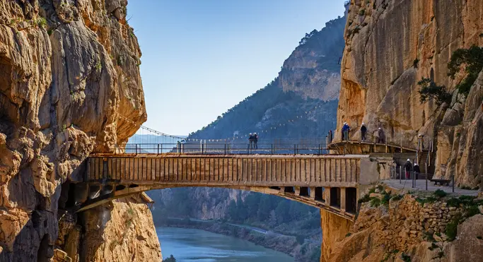 Turistas cruzando el puente colgante del Caminito del Rey sobre el desfiladero.