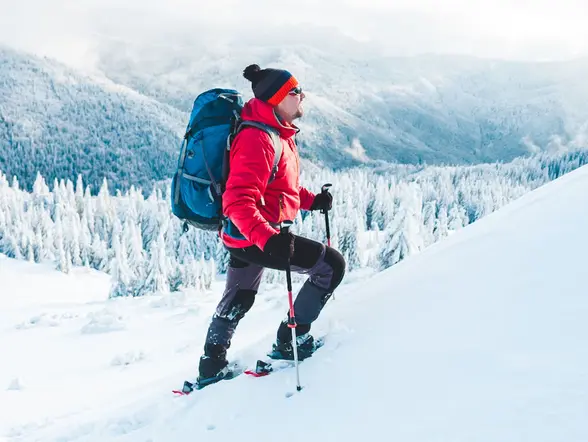 Hombre con chaqueta roja y mochila haciendo una ruta en raquetas de nieve por Sierra Nevada - Ruta en Raquetas de Nieve por Sierra Nevada - Actividades,  Experiencia al aire libre, Ocio y Turismo activo Buendía Andalucía 