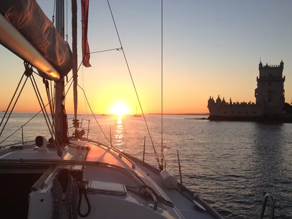 Puesta de sol sobre el río Tajo vista desde un velero, con la Torre de Belém al fondo en Lisboa.